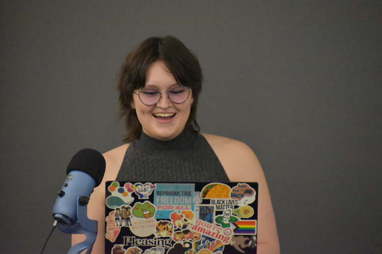 Caitlin Scheresky smiling while standing at mic with open laptop