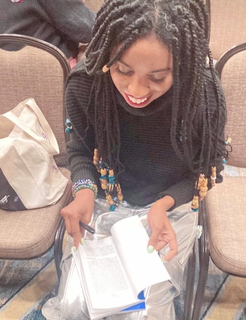 Skye Jackson smiling while opening her book LIBRE to sign