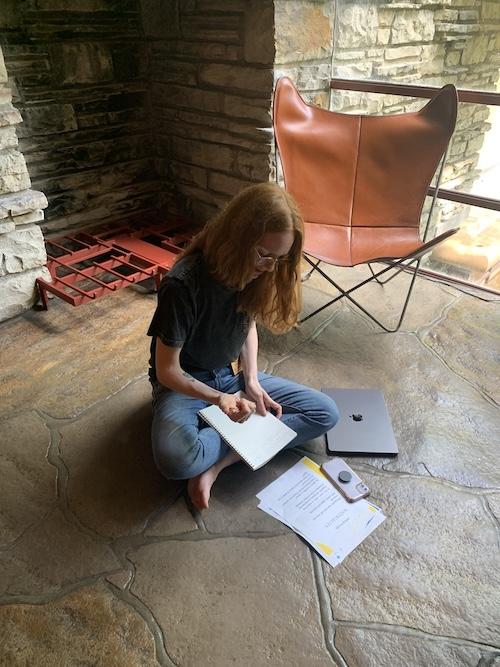Person writing while sitting on stone floor